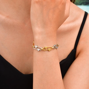 Gros plan d'un bracelet trombone à maillons cœur en or et argent sur un poignet