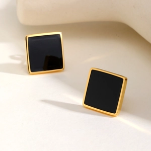 Detailed view of square geometric stud earrings with black enamel and gold finish