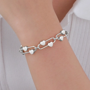 Détail d'un bracelet à chaîne en forme de cœur argenté porté par une femme