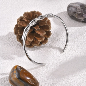 Macro view of silver twisted cable cuff bracelet with woven texture on pine cone