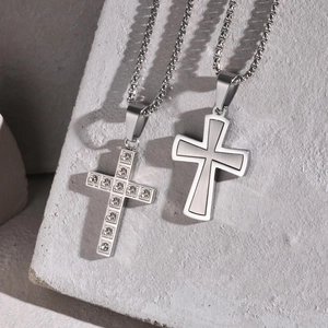 Détail macro de pendentifs croix avec strass pavés et finition en acier brossé