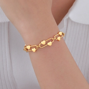 Gros plan d'un bracelet en acier inoxydable doré avec des cœurs portés au poignet