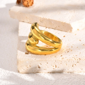 Bague géométrique dorée à plusieurs couches polie sur des blocs de pierre texturés