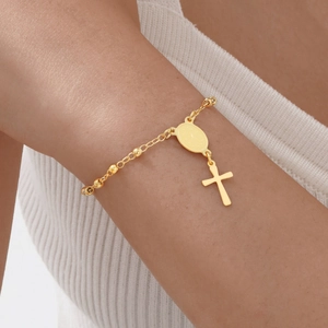 Détail d'un bracelet doré à perles avec médaille de la Vierge Marie et pendentif croix
