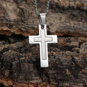 Détail du pendentif croix avec texture métal brossé et bords polis sur une chaîne maille