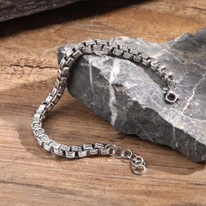 Close-up of polished stainless steel box chain bracelet with lobster clasp on stone