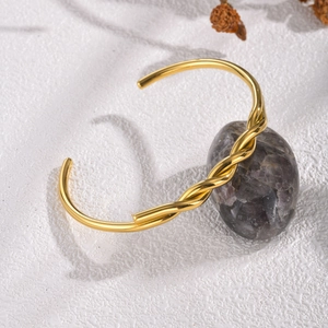 Minimalist gold twisted cuff bracelet with a polished finish and adjustable open design