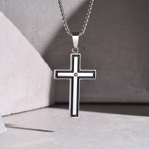 Gros plan d'un pendentif croix en argent avec émail noir et blanc et un petit diamant