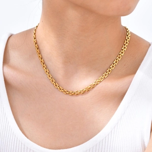 Detail view of gold-plated watchband link chain necklace worn on a female model