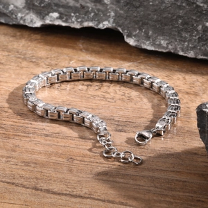 Detail of silver stainless steel box chain bracelet with lobster clasp on wood background
