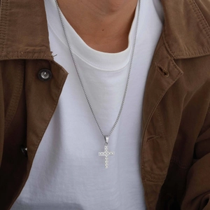 Gros plan d'un collier pendentif croix argenté pour homme avec pierres en zircon blanc