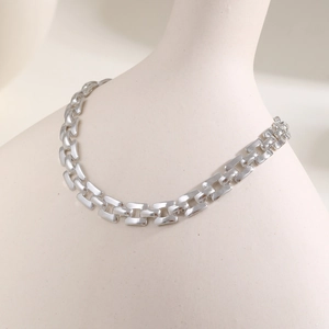 Close-up of industrial style silver thick chain necklace on a white neck model