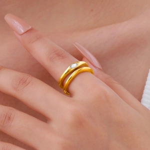 Detail shot of a double-layered gold ring with a bezel-set oval zircon on a finger