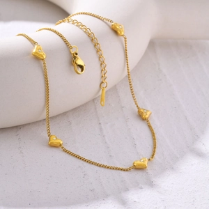 Gros plan détaillé du collier doré à pendentifs cœurs avec zircons et fermoir mousqueton