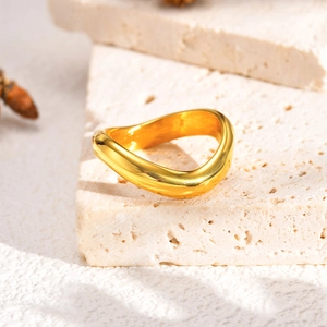 Détail de la bague vagues dorée à trois couches sur un support en pierre texturée