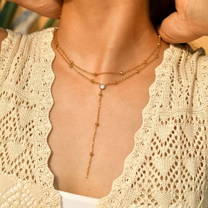 Collier Y double rang doré avec perles et pendentif en zircon porté par modèle