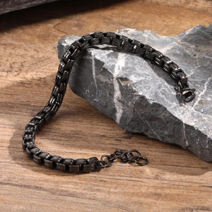 Detail of a matte black stainless steel chain bracelet for men on a natural grey rock