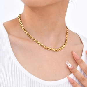 Golden stainless steel watchband style link chain necklace worn on neck by a model