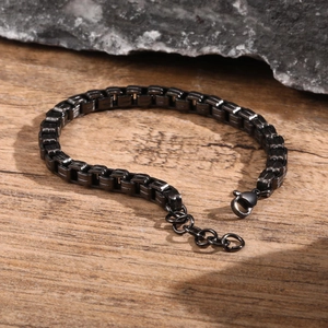 Detail of a black box chain bracelet with lobster clasp on natural wood and stone