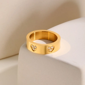 Detail of gold-plated stainless steel ring with brushed texture and zircon hearts