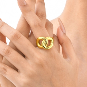 Close-up of interlocking infinity gold ring on finger with polished finish