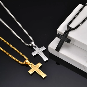 Détail de pendentifs en croix superposés en or, argent et noir sur chaînes box