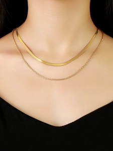 Gros plan d'un collier double épaisseur doré avec maille serpent et torsadée sur modèle
