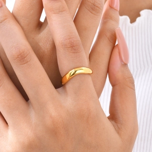 Gros plan d'une bague dorée à trois couches ondulées avec une finition miroir poli