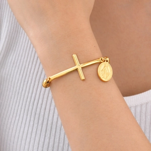 Dettaglio del bracciale a croce dorato con medaglia della Vergine Maria al polso