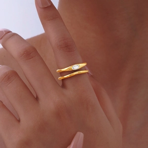 Golden double-layer open ring with an oval zircon stone worn on a female finger