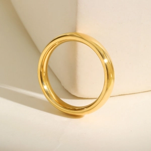 Polished 14K gold stainless steel domed ring displayed on a minimalist stone base