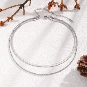 Gros plan d'un collier double épaisseur en acier inoxydable sur présentoir en pierre