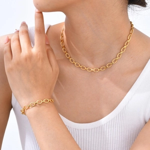 Ensemble collier et bracelet dorés à maillons ovales texturés portés par un mannequin