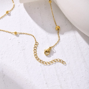 Collier à chaîne croisée plate dorée avec petites perles et fermoir mousqueton sûr