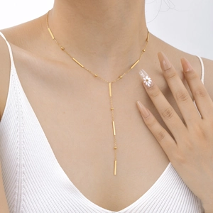 Élégant collier en Y doré avec barres et perles porté par un mannequin en style minimaliste