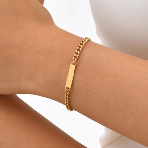 Bracelet d'identité à maillons cubains dorés en acier inoxydable porté par une femme