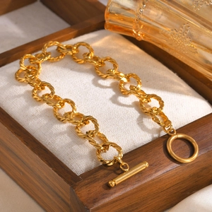 Macro shot of gold twisted link bracelet with toggle clasp in a wooden jewelry box