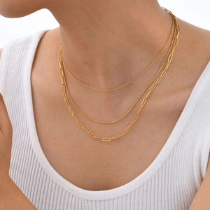 Dreilagige goldene Halskette mit Kreuz-, Schlangen- und Büroklammerkette am Model