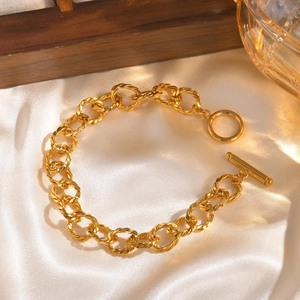 Golden twisted rope link chain bracelet with OT toggle clasp on cream satin background