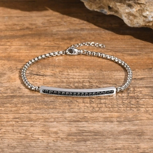 Détail du bracelet chaîne gourmette argentée avec barre en zircon noir sur bois rustique