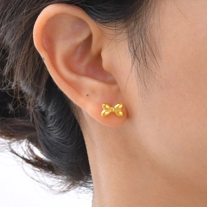 Boucles d'oreilles nœud en acier doré présentées en gros plan sur une femme