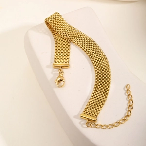 Detailansicht eines goldenen Mesh-Armbands mit großem Karabinerverschluss auf weißem Stein