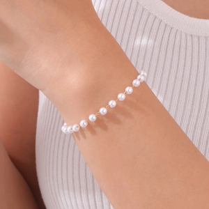 Close-up of elegant gold beaded pearl bracelet worn on wrist with knit clothing