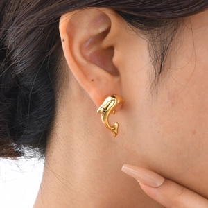 Golden dolphin stud earrings in stainless steel worn by a model for size perspective