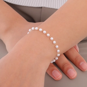 Detail of elegant gold chain bracelet with round white pearls on a model wrist