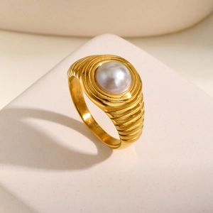 Vue détaillée d'une bague en acier inoxydable doré avec une grande perle blanche centrale
