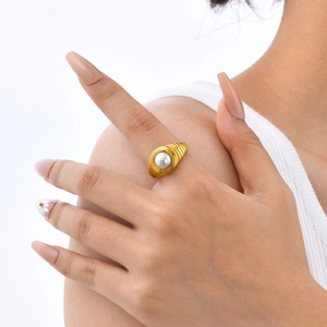 Gros plan détaillé de la bague spirale dorée ornée d'une perle blanche éclatante