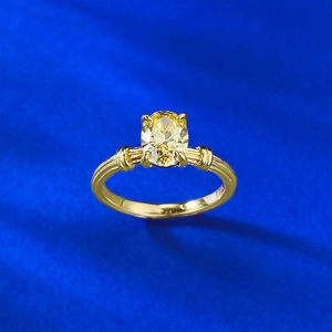 Macro shot of oval yellow gemstone set in a textured gold ring on blue fabric