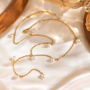 Elegante collana a Y in acciaio inossidabile dorato con perle su sfondo di seta beige