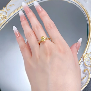 Detail of S925 silver gold-plated ring with an oval yellow gemstone on a finger